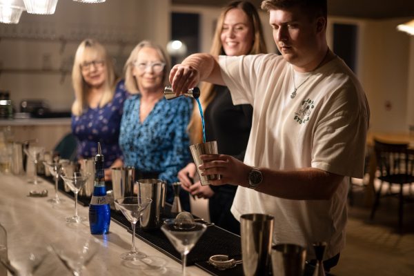 Friends & family on their group stay pouring cocktails in their cocktail masterclass session