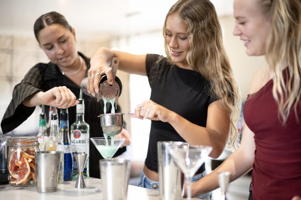 Friends & family on their group stay pouring cocktails in the glasses in their cocktail masterclass session